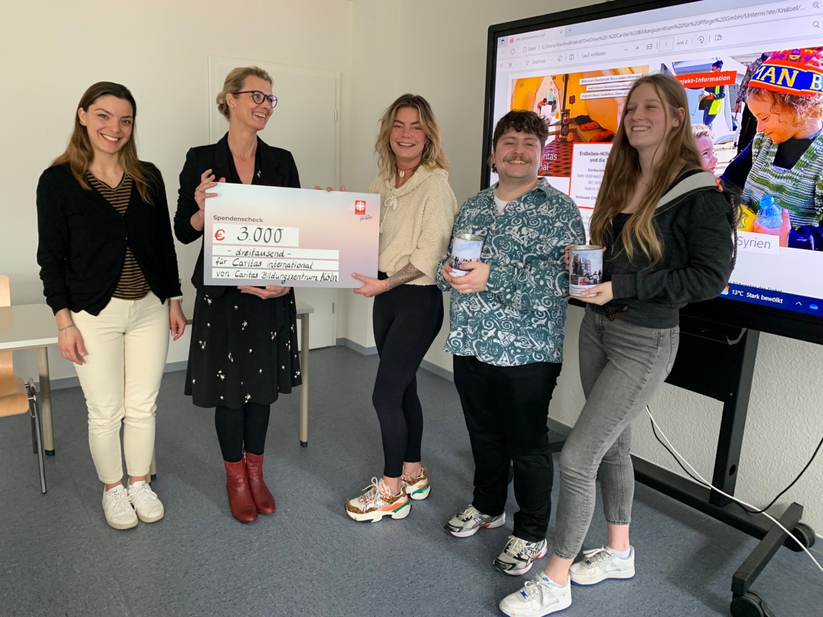 v.l.: Stellvertretend für Caritas international nehmen Sara Sefrin (Fundraising) und Carmen Witte-Yüksel (Vorstandsmitglied Caritasverband Köln) einen symbolischen Scheck in Höhe von 3000 € für die Erdbebenhilfe von Caritas international von den angehenden Pflegefachkräften Lina Ließmann, Andi Baumgarten und Jette Desmedt entgegen. (c) Caritas Bildungszentrum für Pflege